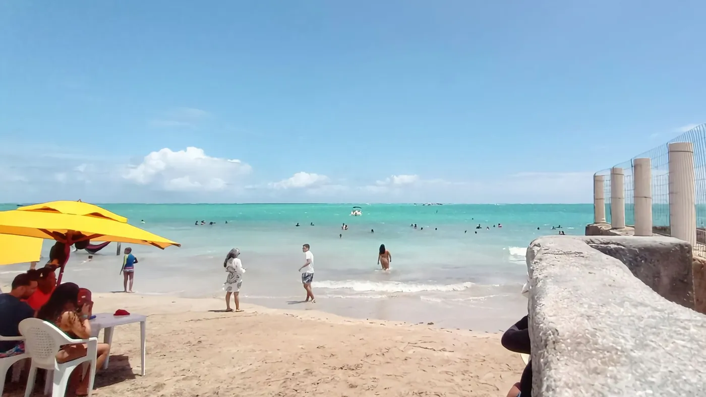 Praia de Maragogi, em Alagoas, com mar esverdeado e banhistas em dia de sol