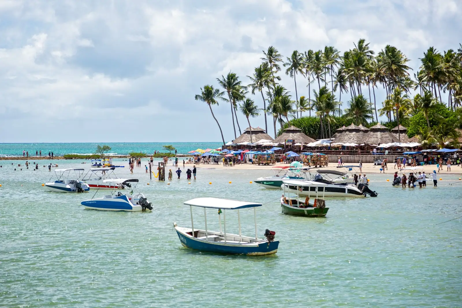 Praia de Porto de Galinhas com jangadas, coqueiros e mar verde