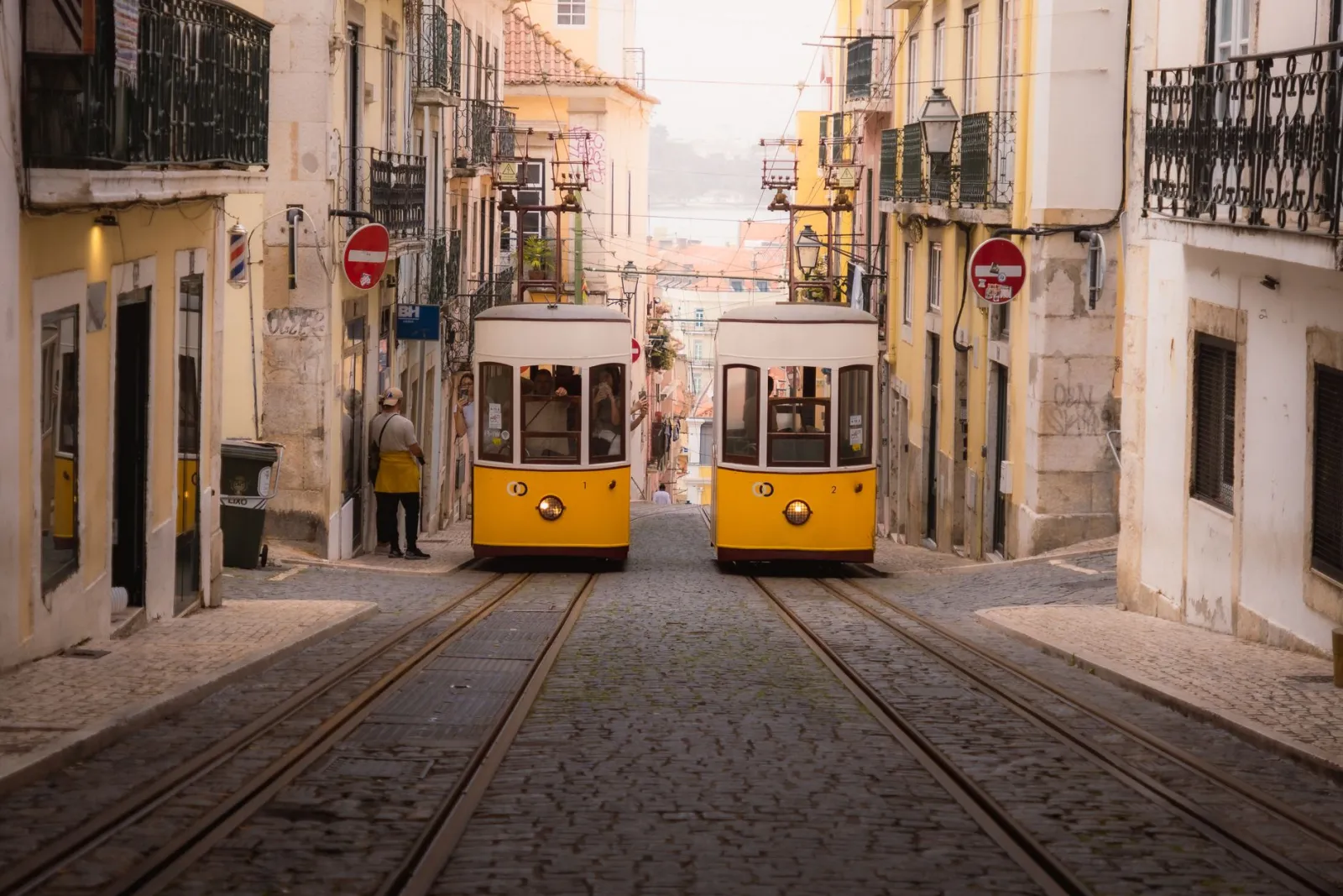 Bondes amarelos em rua histórica de paralelepípedos em Lisboa