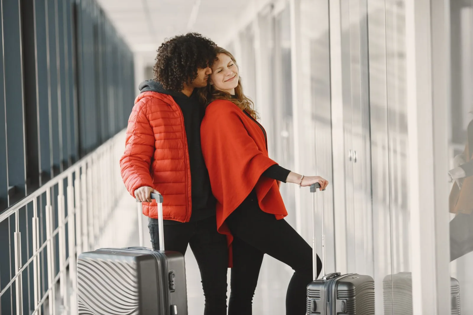 Duas viajantes sorrindo com malas no corredor de um aeroporto