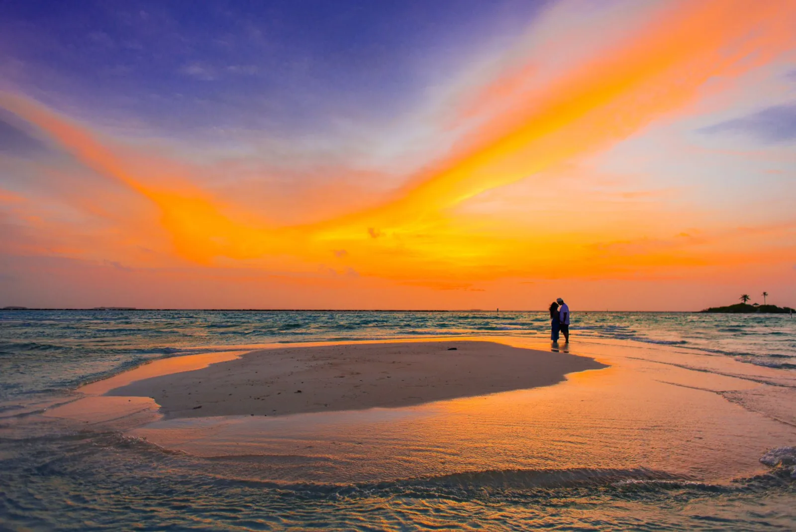 Casal de mãos dadas em praia tropical durante o pôr do sol