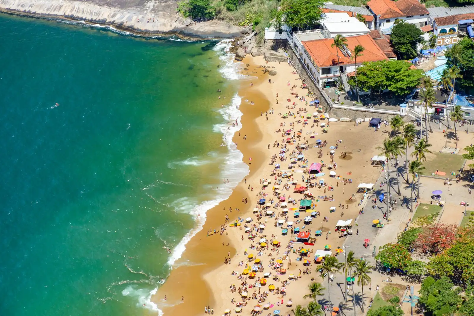 Vista aérea de praia carioca cheia de guarda-sóis em dia de sol
