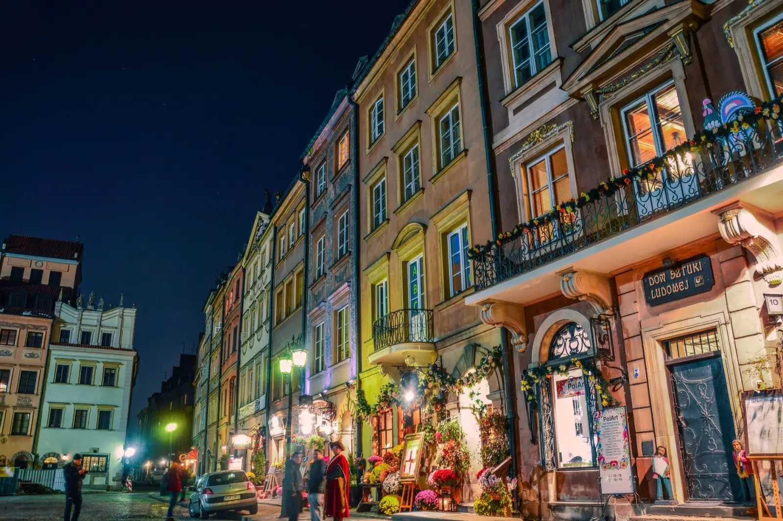 Rua de centro histórico europeu iluminada à noite com prédios coloridos
